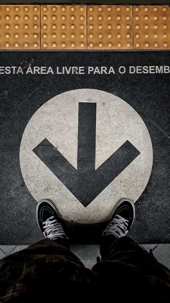 Close-up of a pavement arrow and sneakers indicating direction in a metro area.